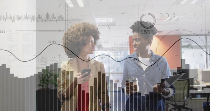 Walking two women in office with smartphone, tablet, cup, wearing tan blazer, with data overlays - Powered by Adobe