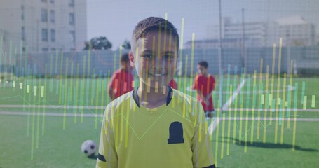 Smiling child in yellow soccer jersey standing on urban field, showing soccer ball, goal overlay
