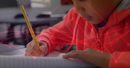 Writing boy in red hoodie marking notebook with yellow pencil in classroom, red overlay, copy space
