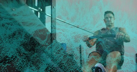 Rowing fit man wearing dark shirt and shorts pulling handle on ergometer in gym, copy space