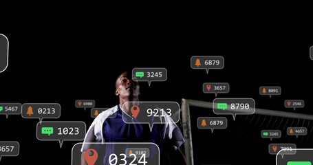 Standing player in blue-jersey white-sleeves looking up spotlit at night with goal and floating-UI