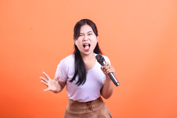 An expressive young woman with a microphone, enthusiastically sings, showing a lot of energy in her...