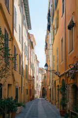 Menton, France - March 25, 2025: Artistic reflection of ornate street lantern in glass with blurred city backdrop and abstract layered composition © Natalie