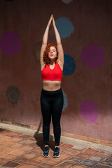 A woman in a red top and black pants is doing yoga poses
