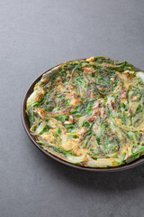 Korean Chive Pancake (Buchujeon) on Dark Stone Background 어두운 배경 위에 담긴 한국식 부추전