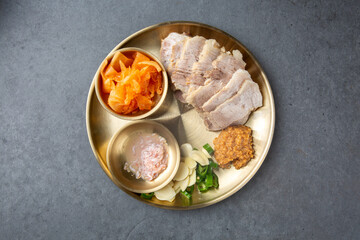 Korean Boiled Pork Belly with Traditional Side Dishes on Brass Plate 전통 놋접시에 담긴 한국식 보쌈 한상