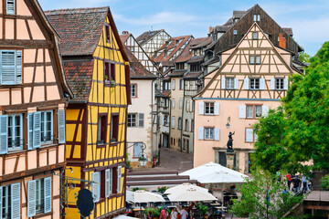 Obraz premium Medieval half timbered buildings of shops and sidewalk cafes near the Schwendi Fountain at Place de l'Ancienne Douane square in the medieval old town of Colmar, France.