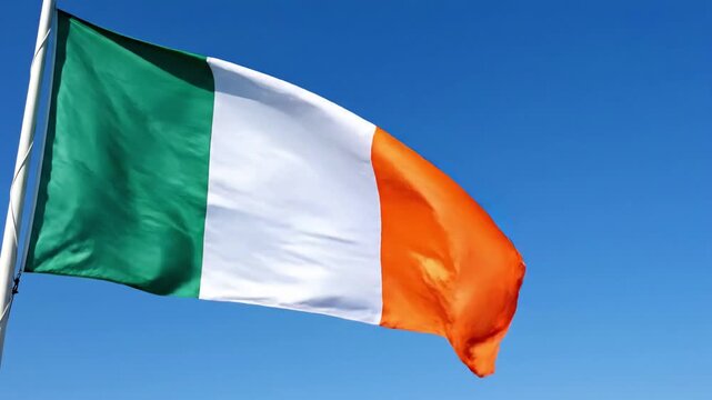 Vibrant Irish flag waving proudly against a clear blue sky, representing national identity concept and European culture