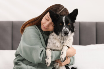 Woman with her cute Border Collie dog on bed at home