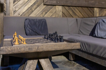  chessboard on coffee table and grey sofa close up, Interior of stylish living room with wooden walls