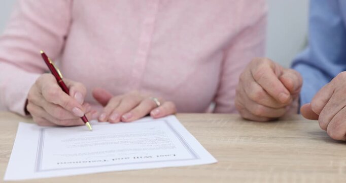 Senior couple signing Last Will and Testament at wooden desk indoors, closeup