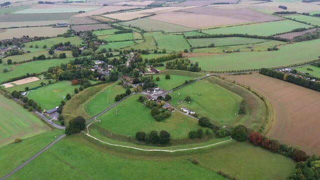 Avebury, Wiltshire, England. Aerial of village and huge prehistoric megalithic stone circle standing stones and henge complex. View to NW. Video fly out up
