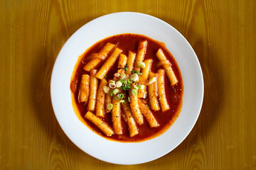 Top down view of a white bowl of Duk bok ki a popular Korean street food made of chewy, cylindrical rice cakes stir-fried in a sweet and spicy sauce