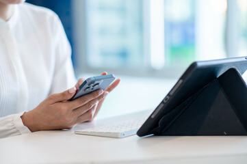 Hands of business woman typing on keyboard use tablet and smartphone