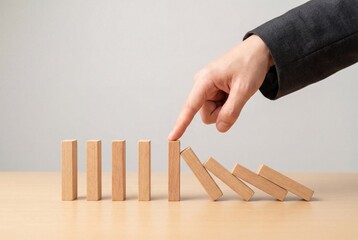 Professional hand stopping falling blocks to halt domino effect and prevent collapse