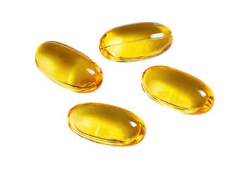 Four golden, oblong gel capsules scattered on a solid black surface