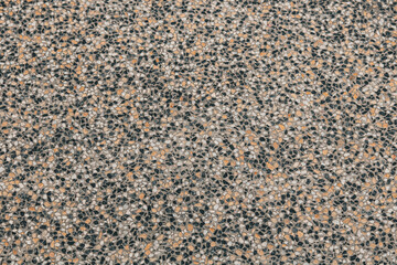 Top-down view of a multi-colored aggregate stone texture. High-quality background featuring tan and black speckled details.
