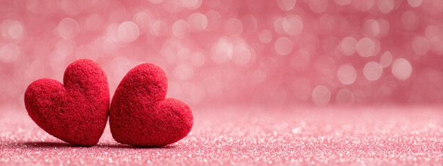 Two red hearts on pink glitter background create romantic and festive atmosphere, perfect for expressing love and affection. blurred background enhances emotional appeal