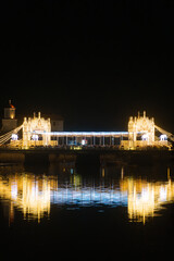 Fototapeta premium Illuminated bridge and waterfront area during night celebration at a lake location