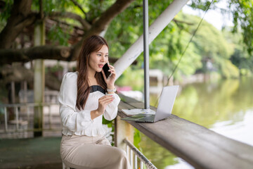 Woman making phone call while working remotely outdoors