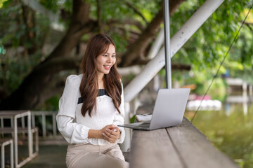 Asian woman working remotely outdoors having video call