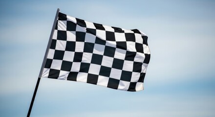 A checkered flag waving in the wind against a clear blue sky.