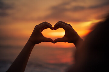 Hand making heart shape on beautiful sunset background. kindness love nature concept	
