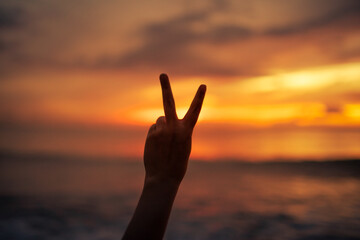 Fototapeta premium Peace Sign Silhouette at Sunset by the Ocean 