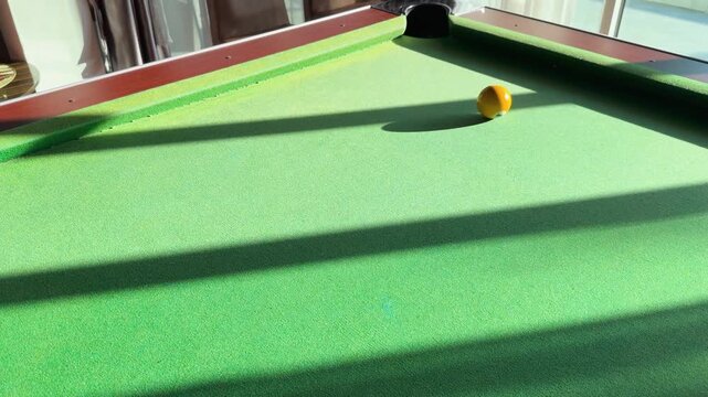 Yellow Billiard Ball Rolling Across Green Felt Table in Slow Motion