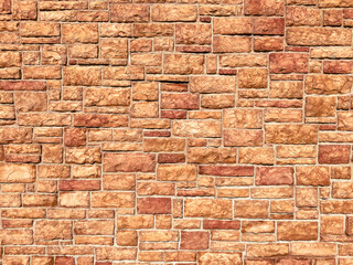 Fototapeta premium A wall made of rectangular brown stones arranged in a neat pattern with rough surfaces and slight color variations creating a rustic textured appearance in daylight