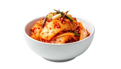 A bowl of vibrant, red kimchi with garlic and green onions on a white background