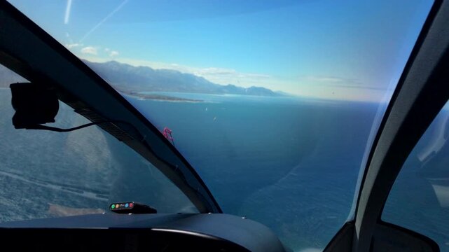 Helicopter cockpit view over open ocean and distant coastline