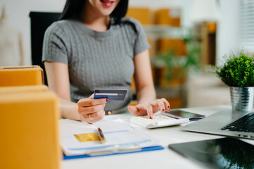 Woman using smartphone and credit card for online shopping and digital payment at home office. Modern ecommerce, small business, fintech, and remote work