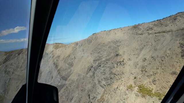 Helicopter window view of rocky mountain slope