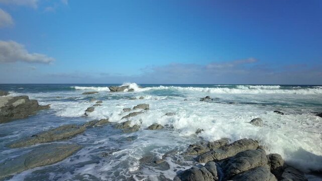 Foamy ocean waves breaking across rocky shoreline