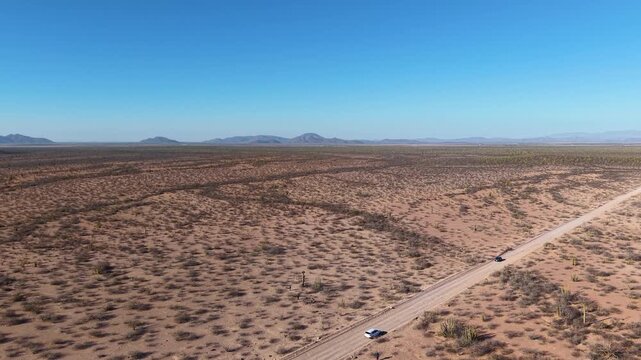 toma de dron de un camino de terracer&iacute;a en medio del desierto bajo un hermoso cielo azul con monta&ntilde;as en el horizonte en el estado de Sonora, M&eacute;xico.