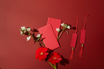Chinese New Year flat lay featuring red envelopes, floral branches and festive elements decorated on red background. Clean layout for branding and advertising.