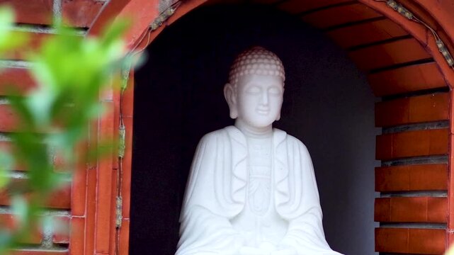 White Buddha Statue Resting in a Red Brick Wall Niche