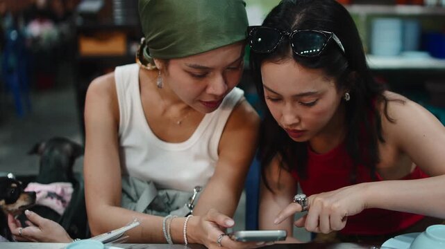 Asian women friends using a smartphone at restaurant