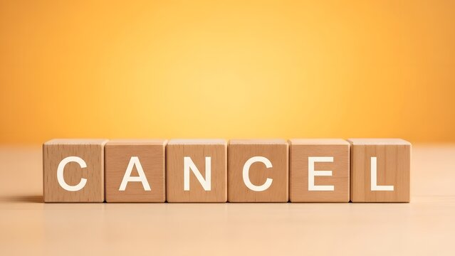 Wooden blocks spelling 'CANCEL' on a light surface with a warm orange background, representing the concept of cancellation or termination.
