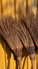 Traditional Coconut Leaf Broom Isolated on Yellow Background, Handmade Natural Cleaning Tool with Minimal Studio Composition