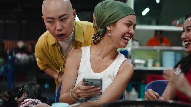 Three asian friends laughing while using smartphone