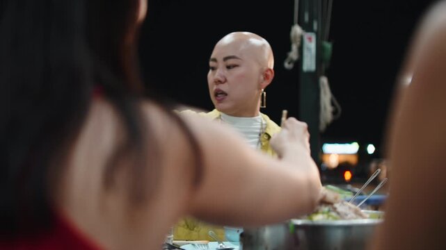 Asian friends eating moo krata at night