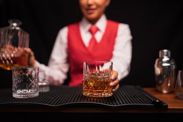 A female bartender is pouring whiskey into a glass in a restaurant.