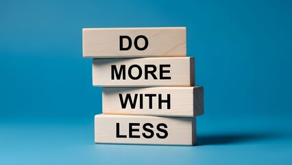 Wooden blocks stacked vertically spelling out the phrase 'DO MORE WITH LESS' against a vibrant blue background, symbolizing efficiency and productivity.