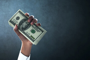 Businessman hand holding money with on dark background