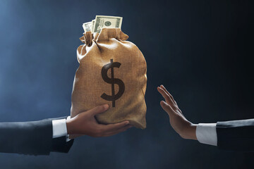 Business man hand giving money bag on dark background, anti corruption