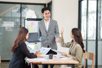A businessman is standing at the office giving a presentation.
