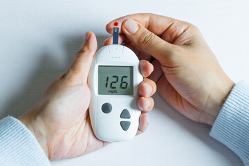Woman's hands checking diabetes and hyperglycemia with digital blood sugar meter. Healthcare and medical concept	