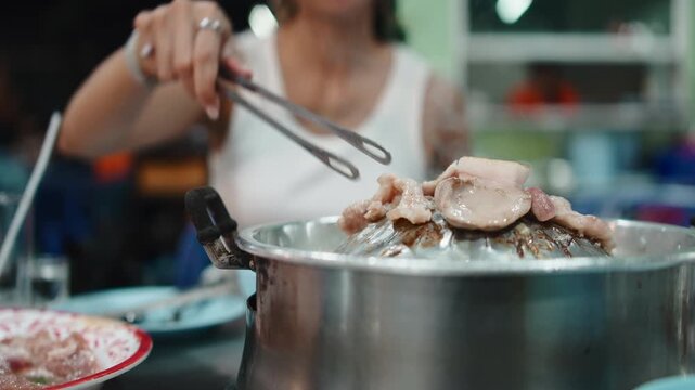 Woman cooking delicious moo kra ta thai barbecue pork